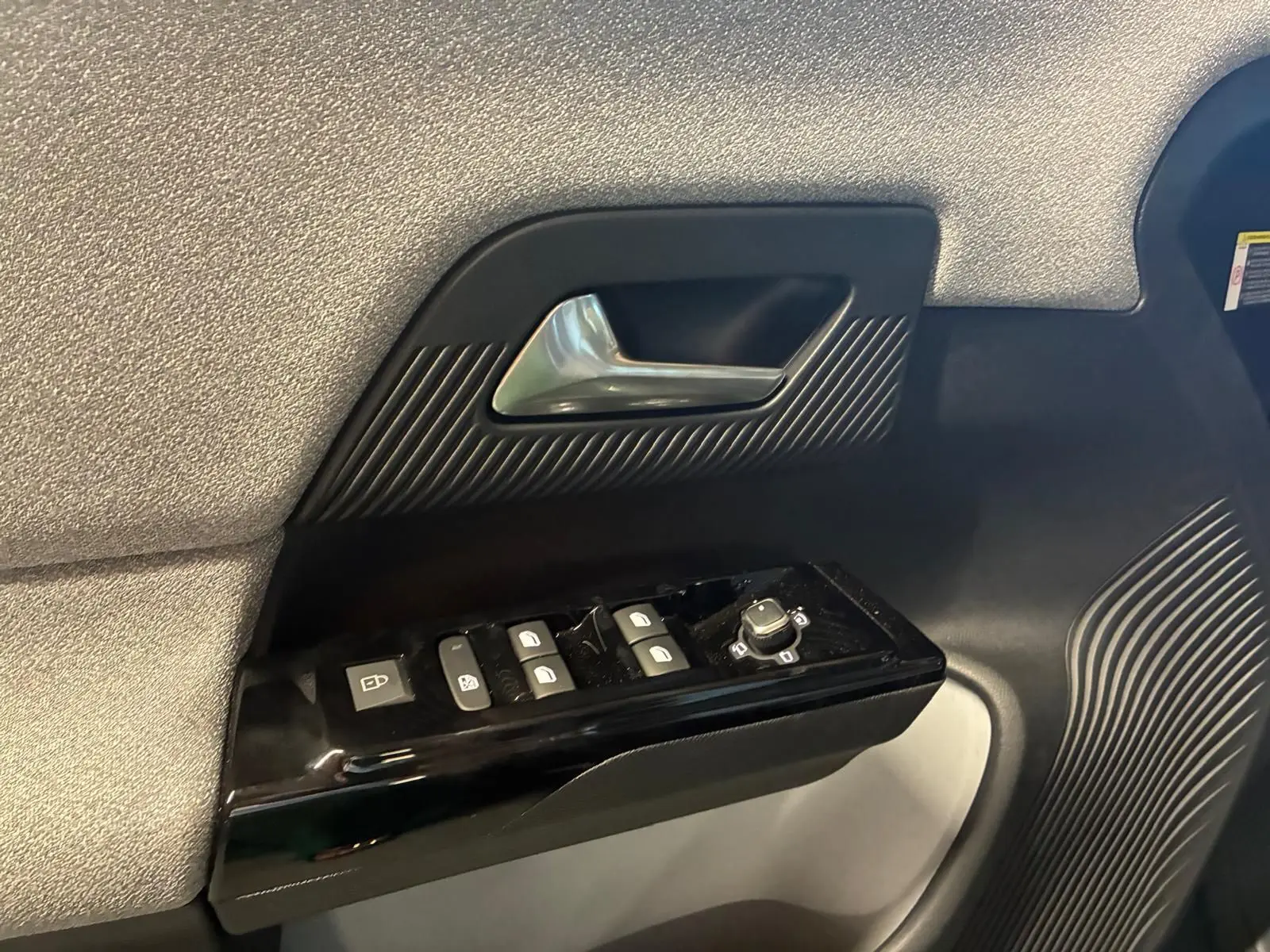 Détail de la porte côté gauche de la Citroën C5 Aircross 1.2 Hybrid 145 BVA Max avec commandes de vitres et poignée argentée.