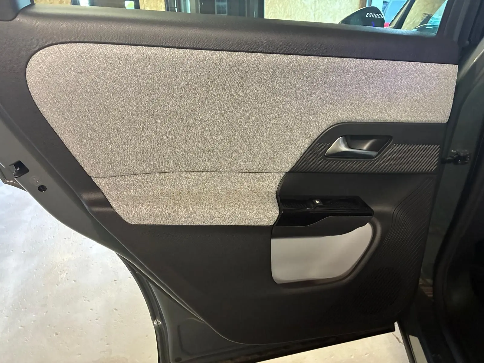 Vue intérieure côté gauche de la porte arrière du Citroën C5 Aircross 2026, tissu gris clair et plastique noir.
