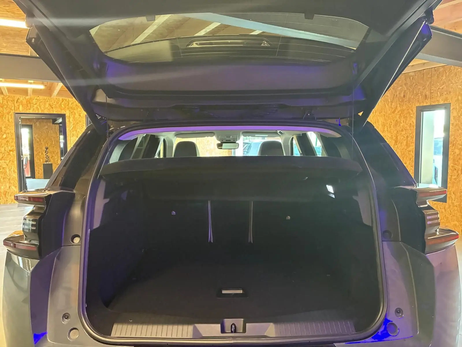 Coffre ouvert vu de l'arrière d'un Citroën C5 Aircross Vert Astoria Metal dans un intérieur en bois.