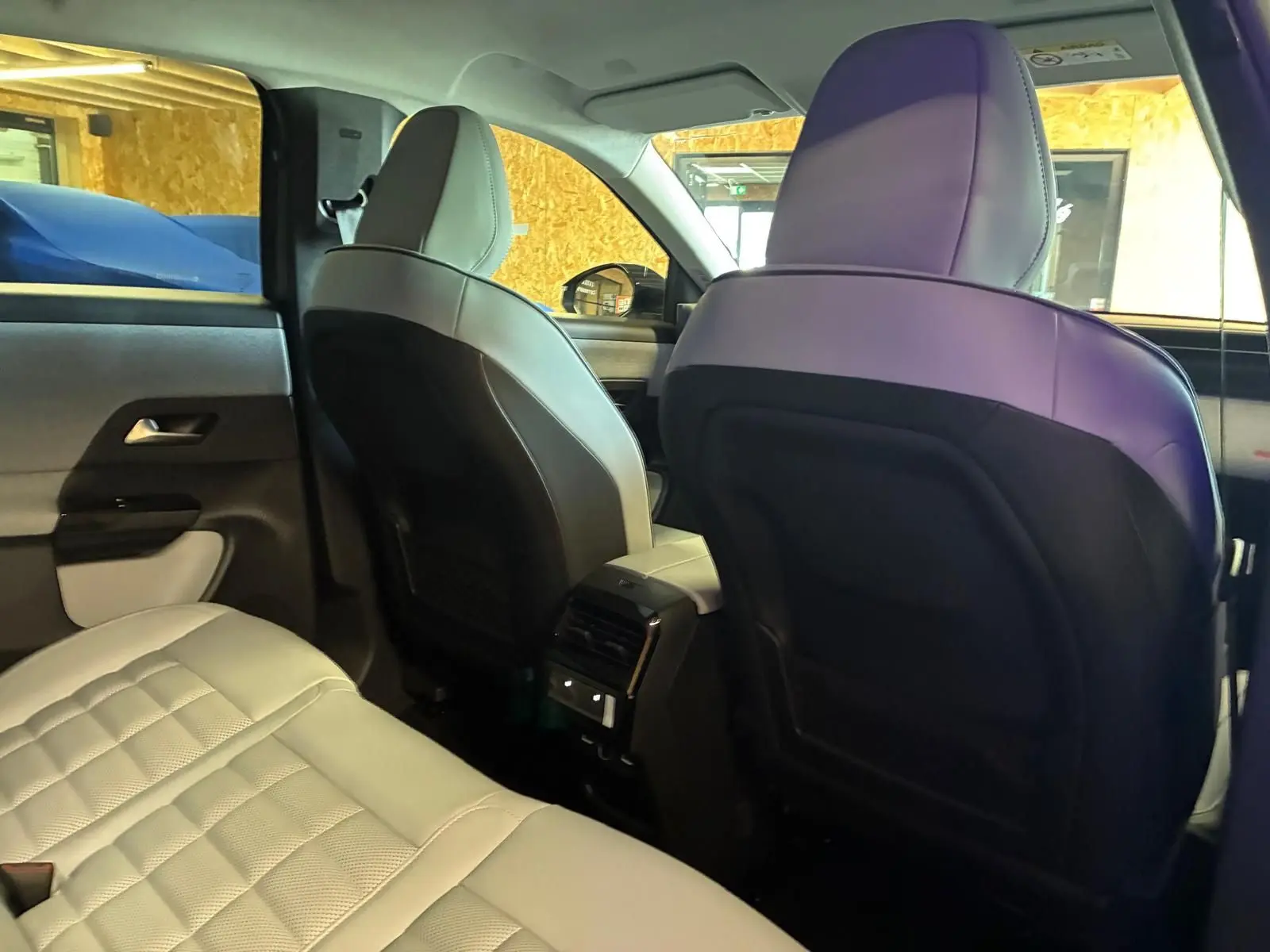 Vue intérieure arrière du Citroën C5 Aircross 2026, sièges en cuir beige clair avec dossier noir et console centrale avec aérateurs.