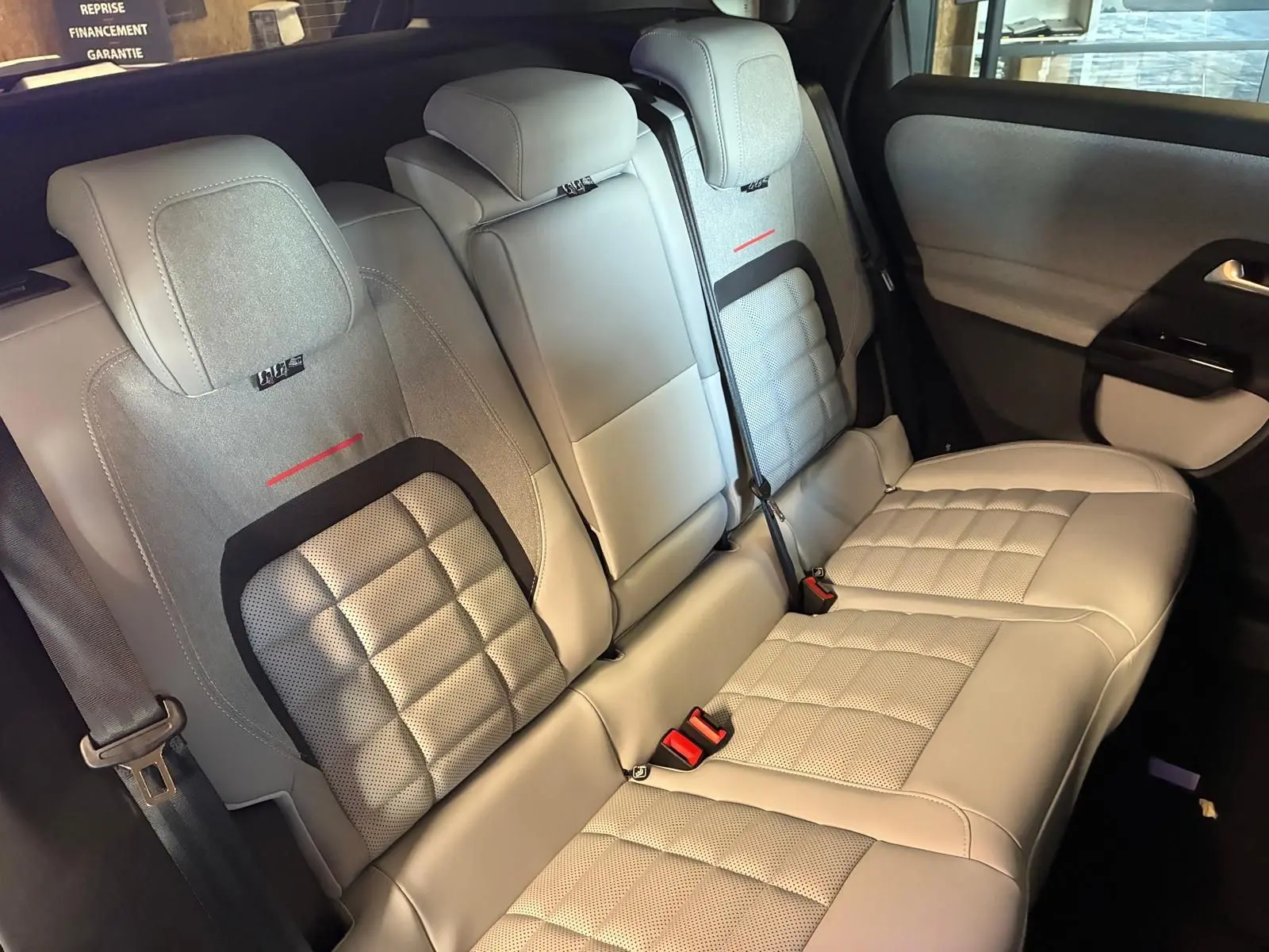 Vue intérieure des sièges arrière gris clair du Citroën C5 Aircross 2026, avec surpiqûres et ceintures visibles.
