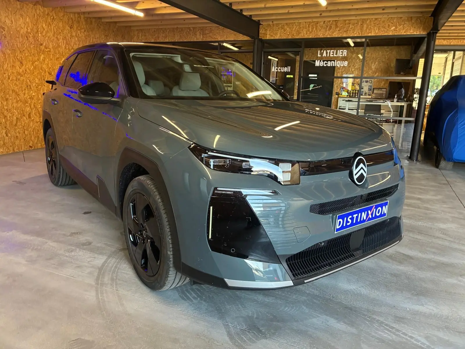 Citroën C5 Aircross 1.2 Hybrid 145 BVA Max vert Astoria métal, vue 3/4 avant droit en intérieur d'atelier.