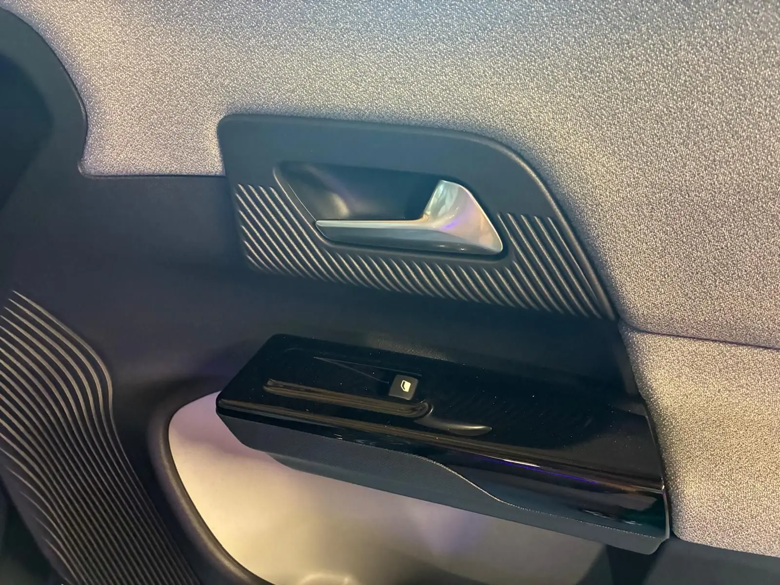 Détail de la poignée intérieure côté gauche avec commande de vitre noire sur porte gris clair du Citroën C5 Aircross 2026.