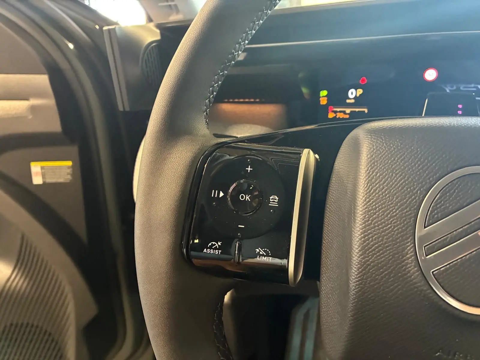 Gros plan sur la commande multifonction gauche du volant en cuir noir du Citroën C5 Aircross 2026, détails des boutons assist et limit.