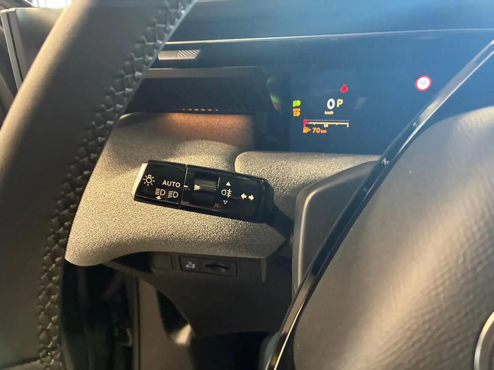 Gros plan sur la commande des feux et clignotants à gauche du volant dans le cockpit du Citroën C5 Aircross vert Astoria.