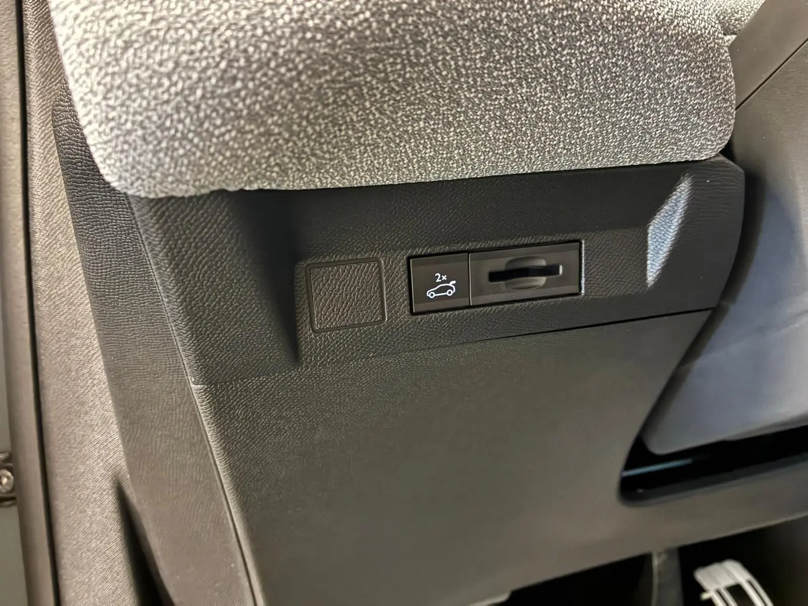 Détail intérieur montrant le bouton d'ouverture électrique du hayon sur la partie inférieure côté conducteur du Citroën C5 Aircross hybride.