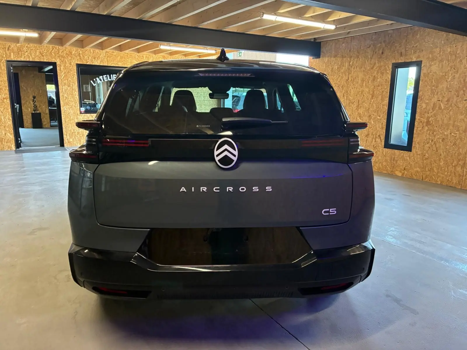 Vue arrière d'un Citroën C5 Aircross 2026 vert Astoria Metal, avec logo et nom du modèle bien visibles dans un intérieur lumineux.