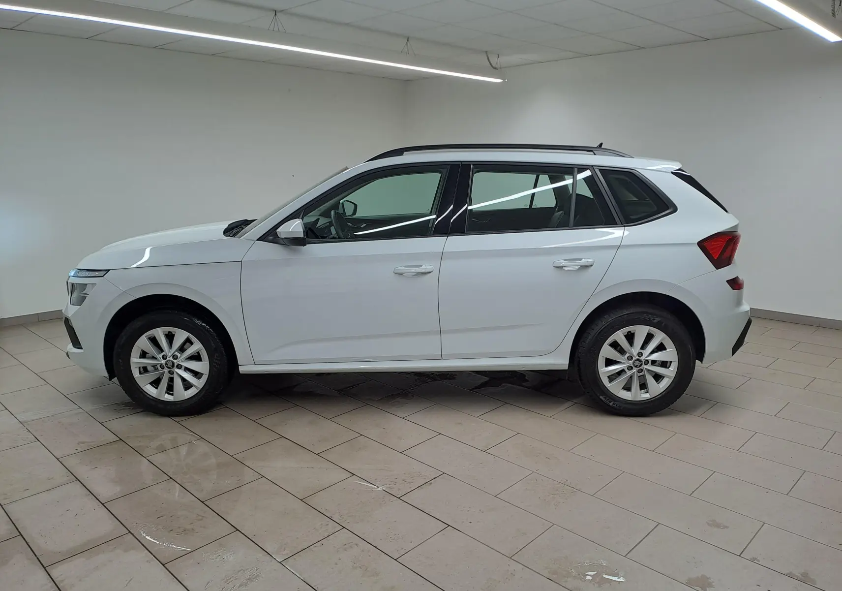 Vue latérale droite du SUV blanc SKODA KAMIQ 1.0 TSI 116 DSG7 2025 avec toit noir et jantes alliage.