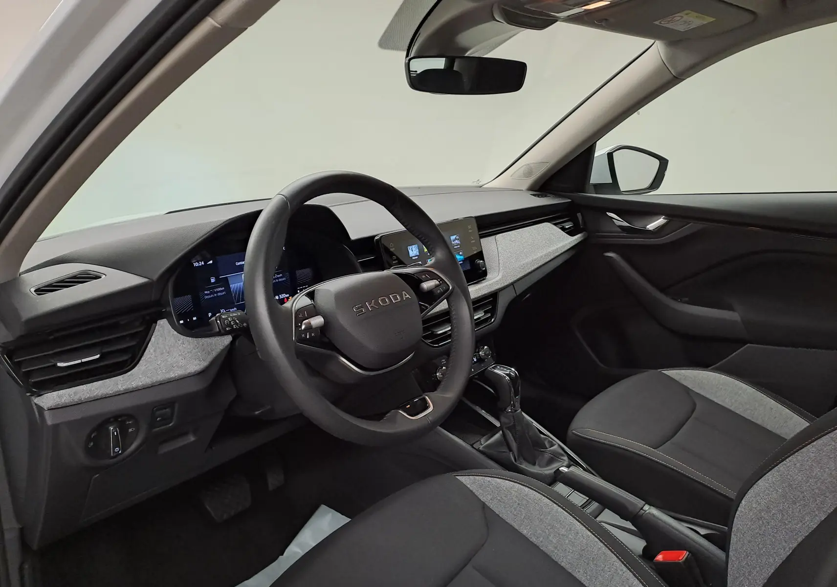 Intérieur de la Skoda Kamiq 2025 vu côté conducteur, tableau de bord moderne avec écran tactile et volant multifonction.