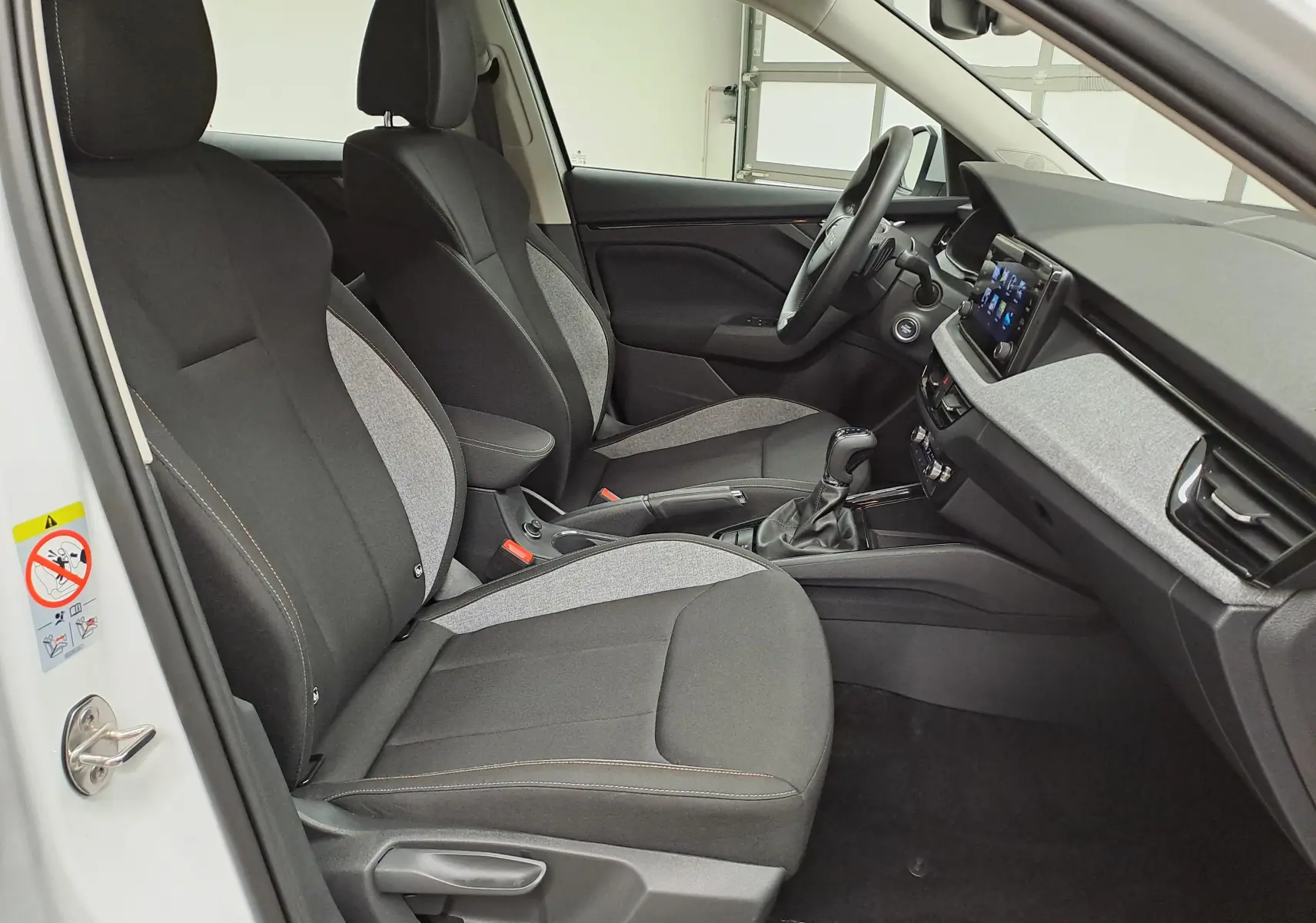 Vue intérieure côté conducteur du Skoda Kamiq blanc Lune 2025, mettant en valeur les sièges bi-matière et la console centrale.