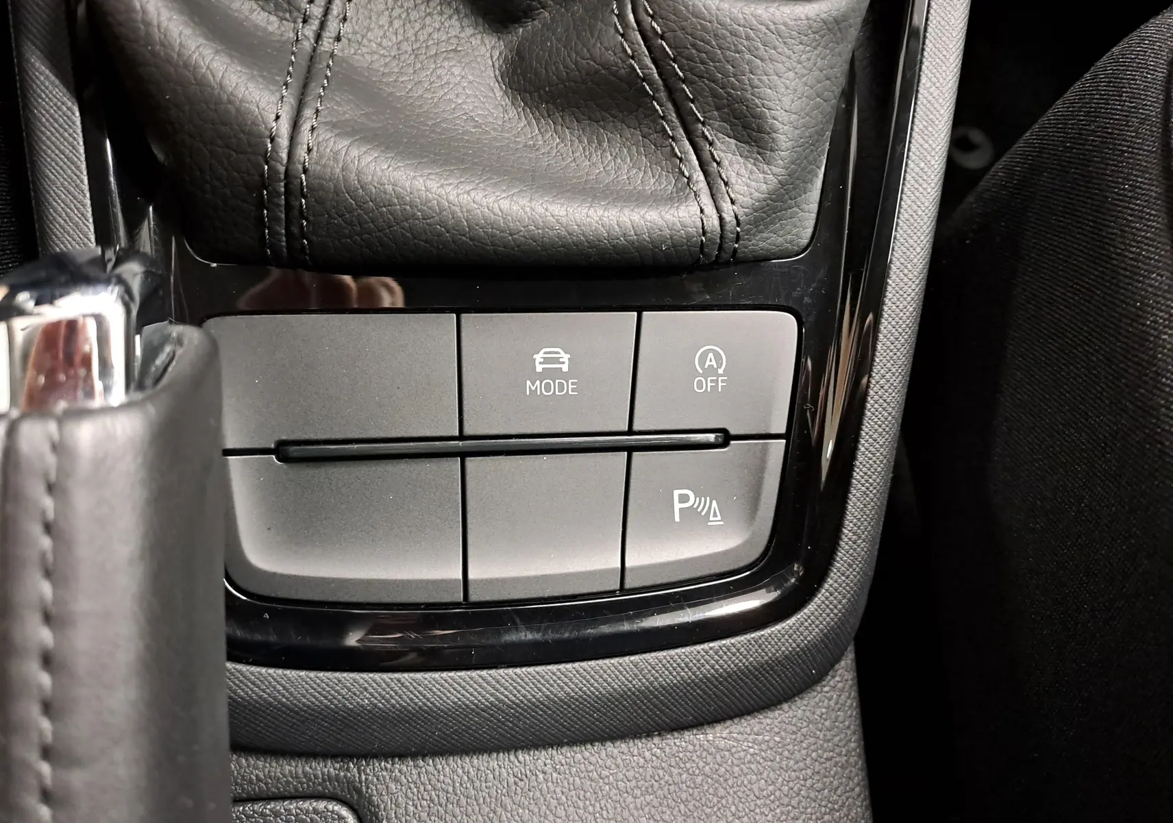 Gros plan sur les commandes de la console centrale du Skoda Kamiq 2025, avec bouton mode conduite et radar de stationnement.