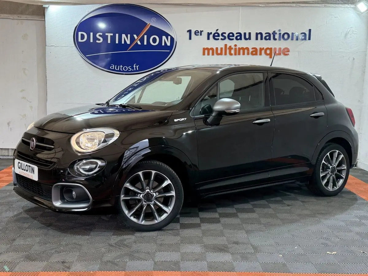 Vue de profil droit d'une FIAT 500X noire finition Sport avec jantes alliage et rétroviseurs argentés dans un showroom.
