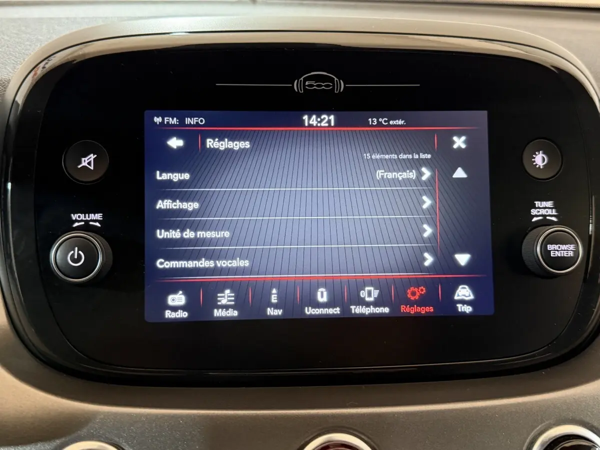 Écran tactile central de la Fiat 500X noir affichant le menu réglages avec commandes vocales en français.