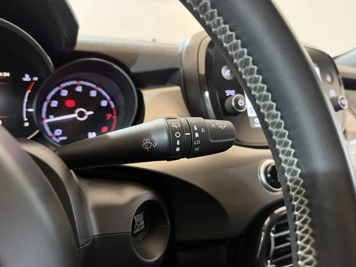 Gros plan sur la manette d’essuie-glace côté gauche du tableau de bord noir du Fiat 500X 2021, volant cuir visible.