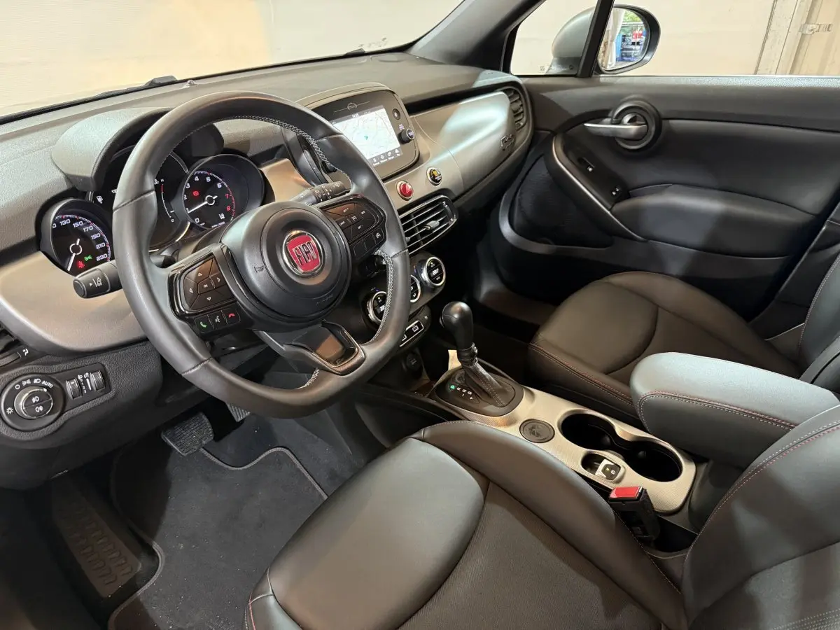 Vue intérieure côté conducteur du Fiat 500X 2021 avec tableau de bord noir et écran tactile central.
