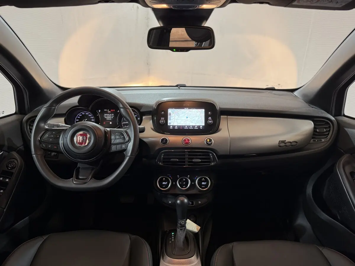 Vue intérieure frontale du tableau de bord noir et gris de la FIAT 500X 2021 avec écran tactile et volant multifonctions.
