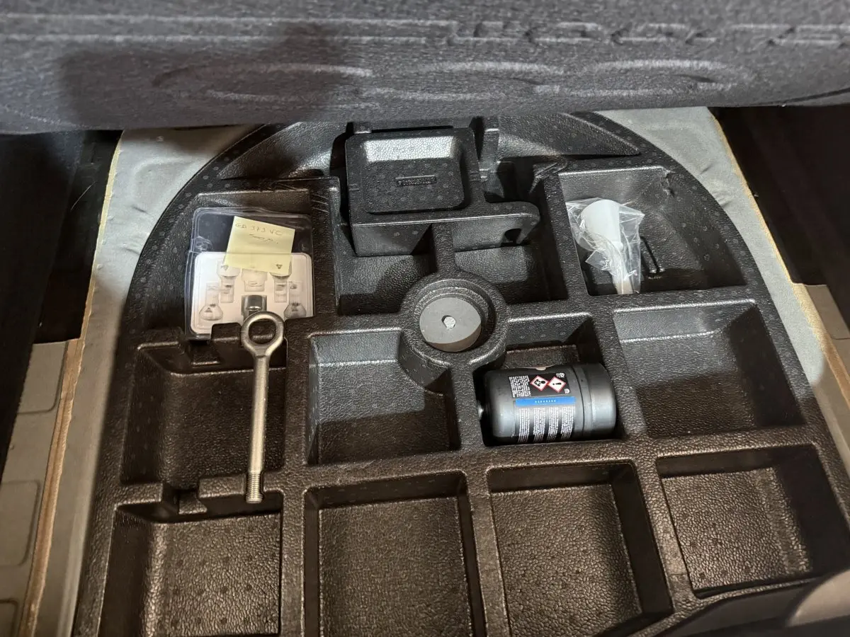 Rangement sous le coffre d'une FIAT 500X noire 2021, montrant l'emplacement des outils et accessoires.
