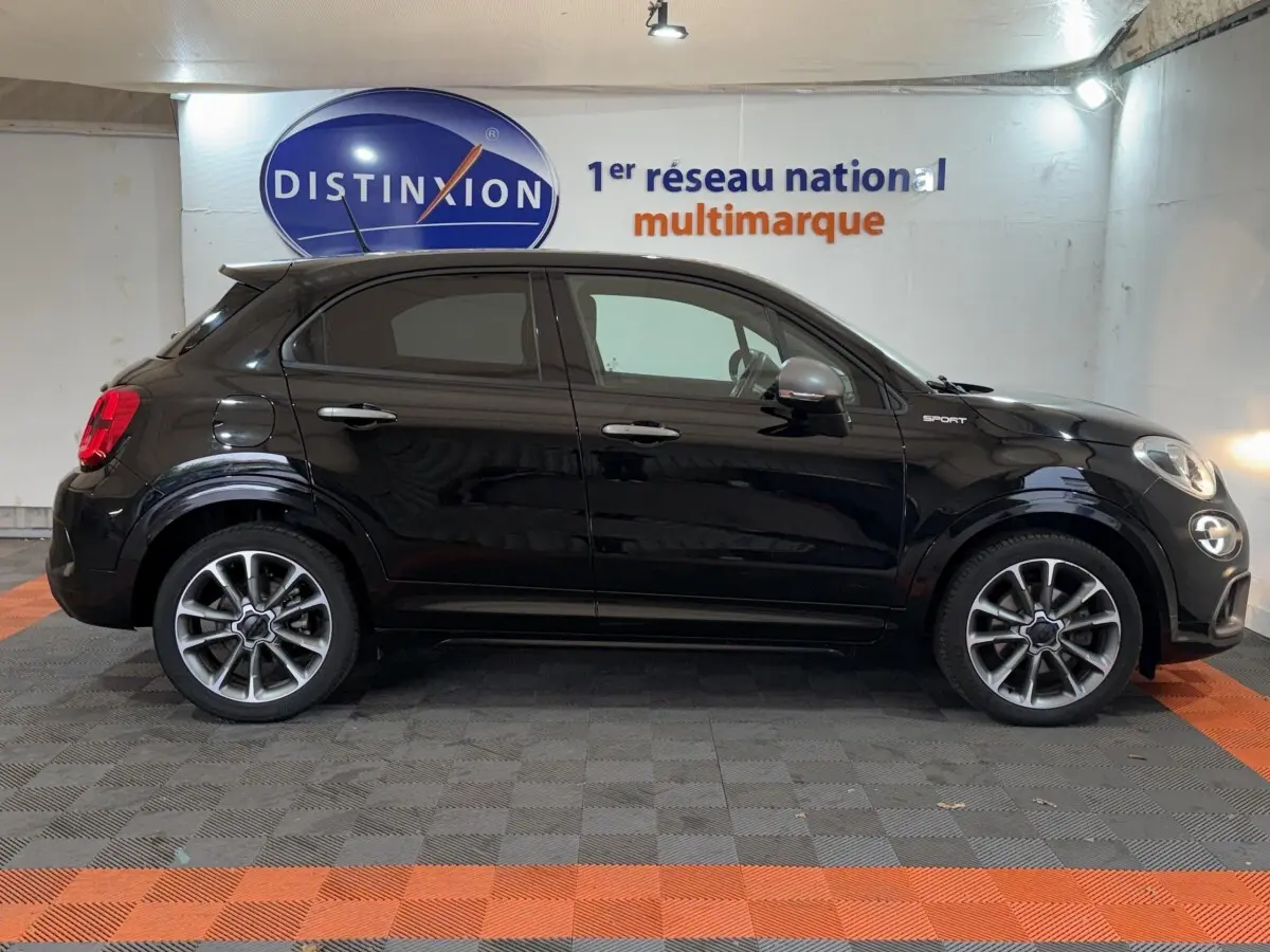 Profil droit d'un FIAT 500X noir 2021 avec badge Sport et jantes alliage distinctives en showroom.