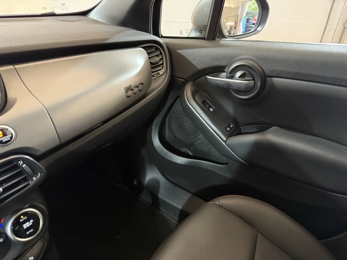 Vue intérieure côté passager du tableau de bord noir mat et de la portière avec logo 500 visible sur une FIAT 500X 2021.