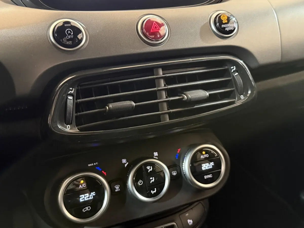 Gros plan sur la console centrale noire du Fiat 500X 2021, montrant les commandes de climatisation et les aérateurs.