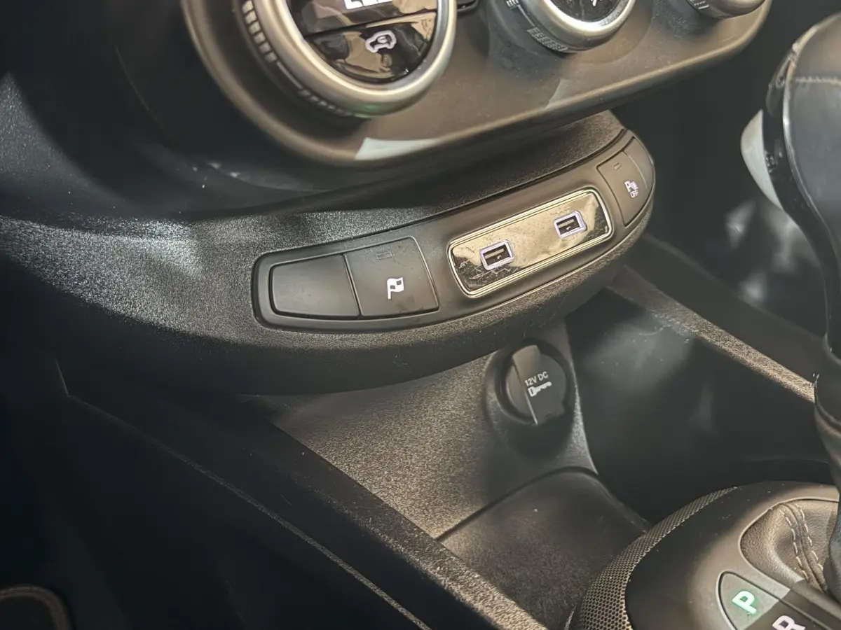 Gros plan sur la console centrale noire du Fiat 500X 2021 avec ports USB et prise 12V visibles.