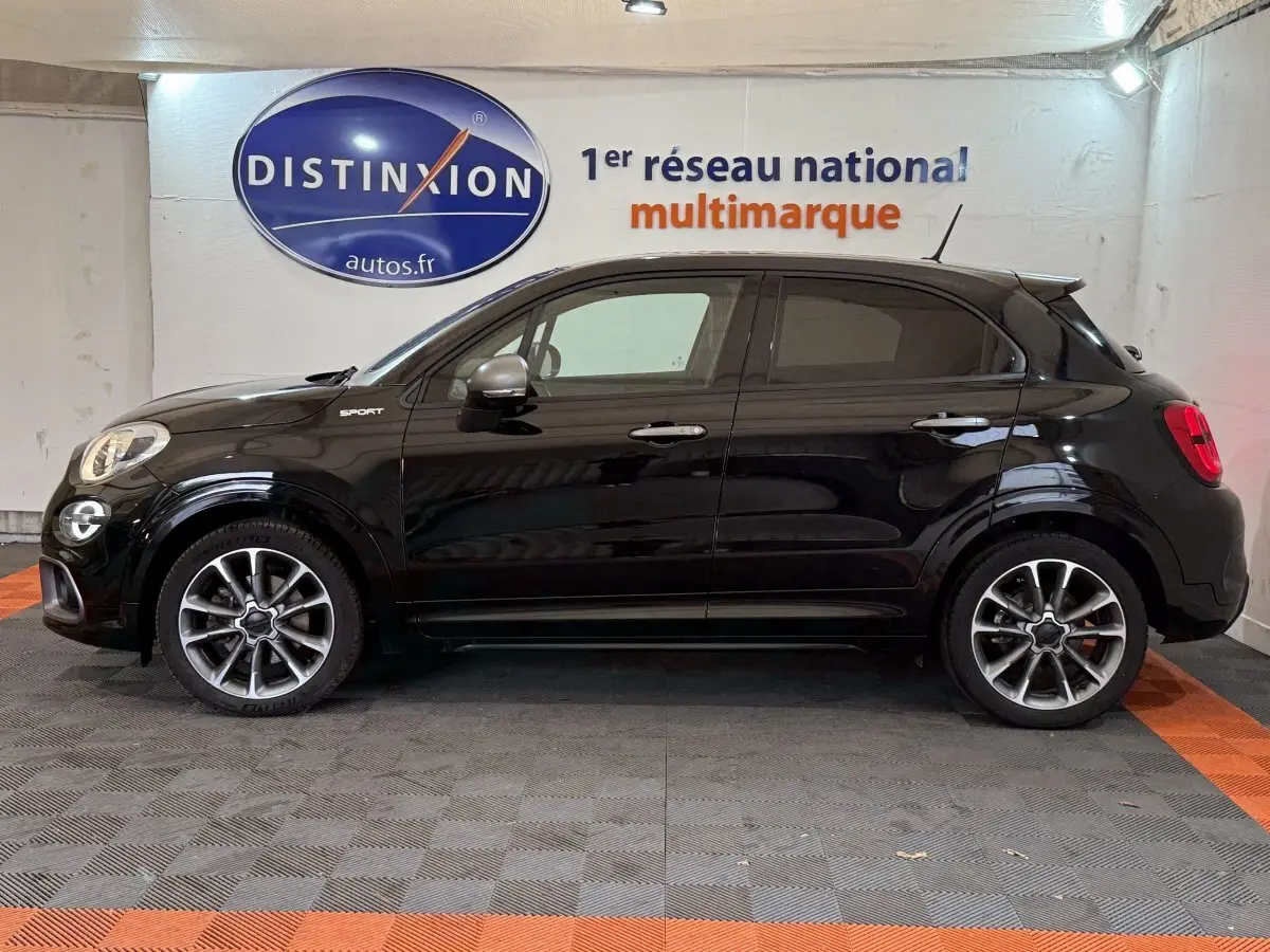 Profil côté gauche d'une FIAT 500X Sport noire avec jantes alliage et rétroviseurs argentés dans un showroom.