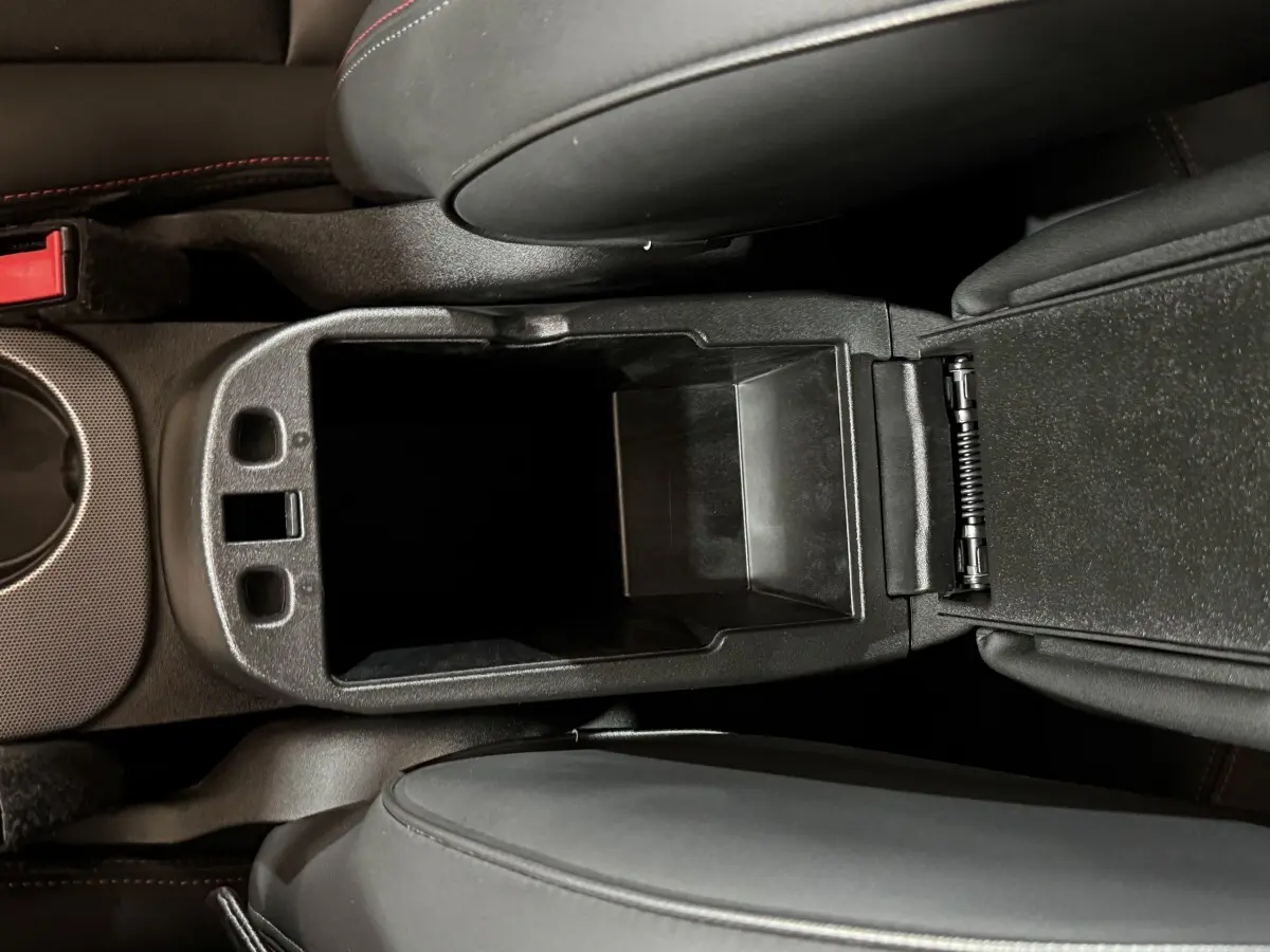 Vue plongeante sur le rangement central noir ouvert entre les sièges avant d'un Fiat 500X 2021.