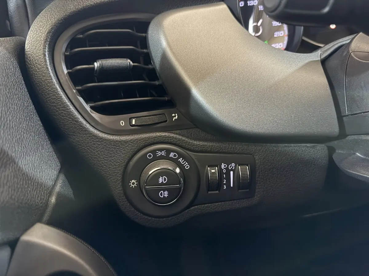 Gros plan sur la commande des phares et la sortie d’air à gauche du tableau de bord noir du Fiat 500X 2021.