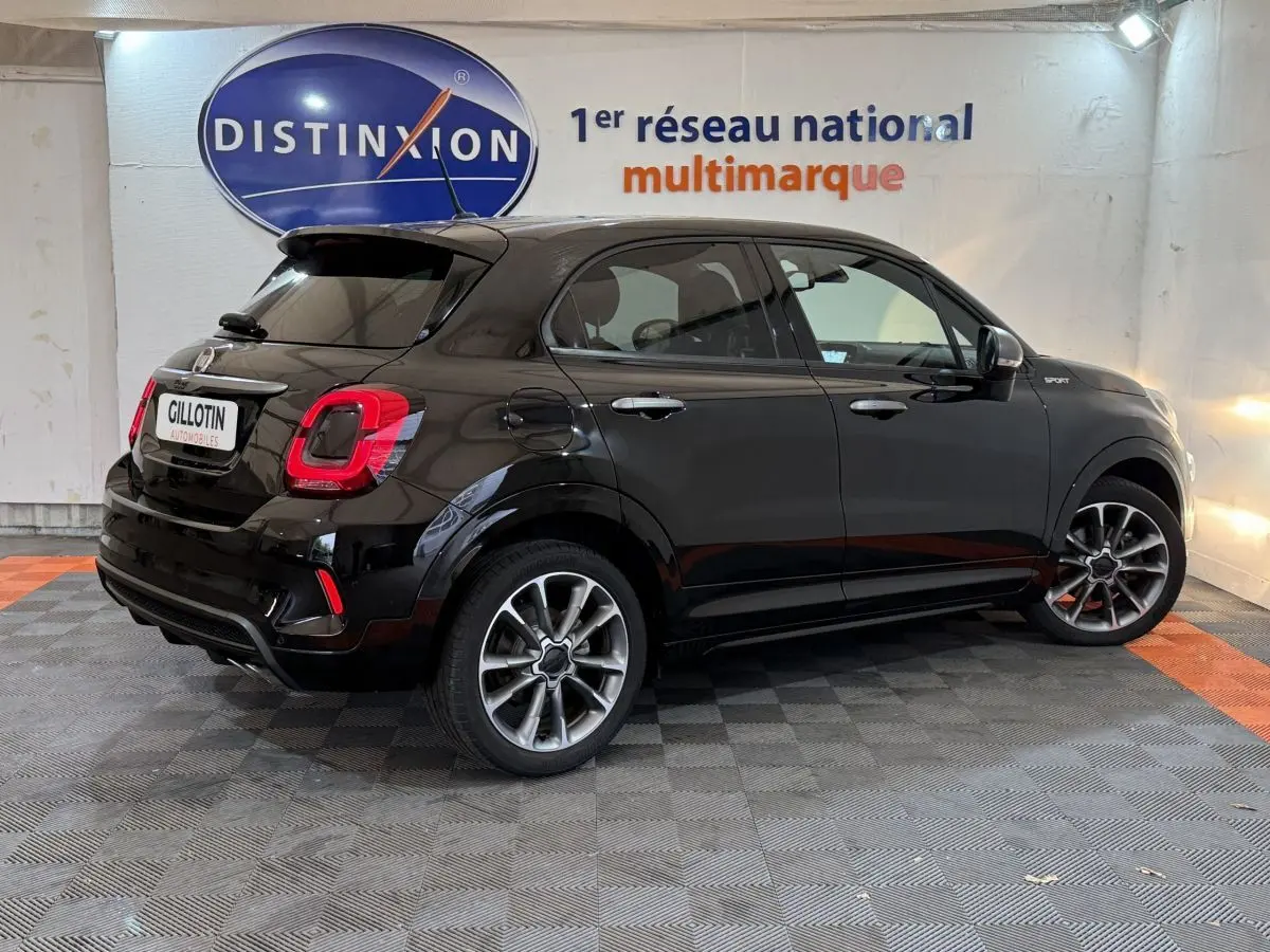Vue 3/4 arrière droite d'une FIAT 500X noire version Sport, avec jantes alliage et logo distinctif sur l'aile avant.