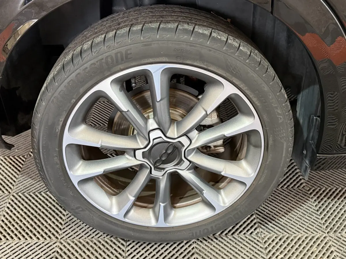 Gros plan sur la roue avant droite noire de la FIAT 500X 2021 avec jante alliage argentée au design moderne.