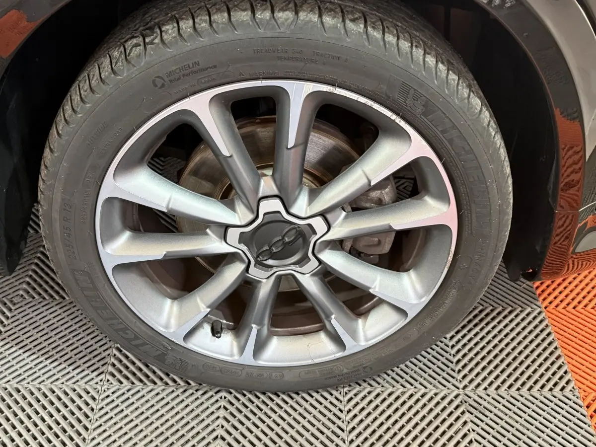 Gros plan sur la jante alliage argentée et le pneu Michelin du côté avant droit d'une FIAT 500X noire Sport 2021.