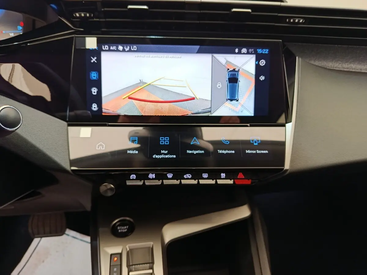 Vue intérieure centrée sur l’écran tactile et la console centrale de la Peugeot 308 blanche avec affichage caméra de recul.