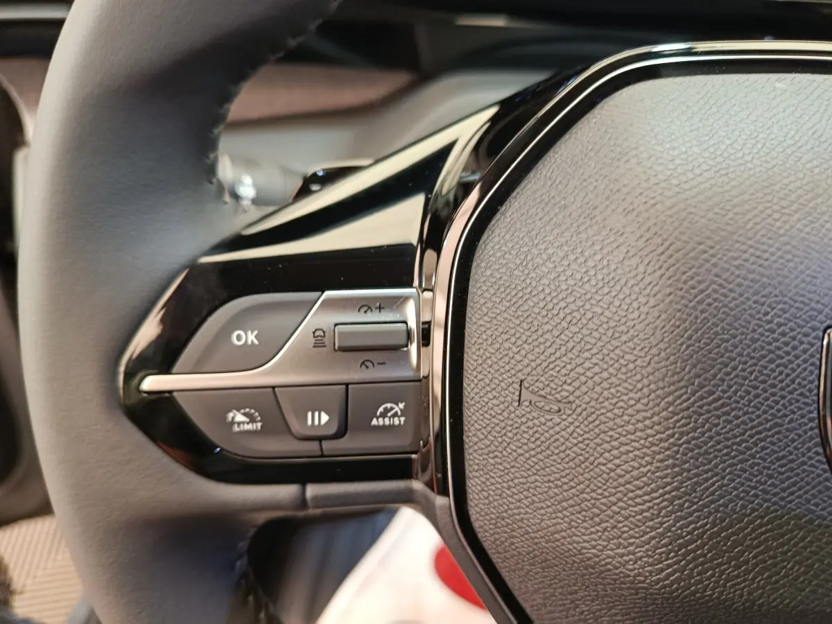 Gros plan sur le côté gauche du volant cuir multifonctions de la Peugeot 308 BlueHDi 130 CH EAT8 Allure 2026.