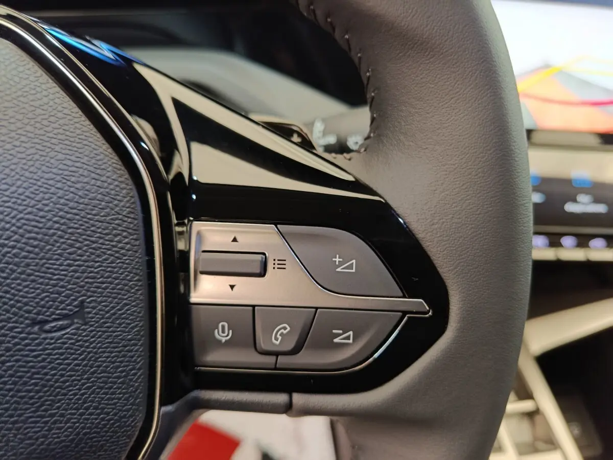 Gros plan sur le côté droit du volant cuir multifonctions de la Peugeot 308 blanche, avec commandes audio et appel.