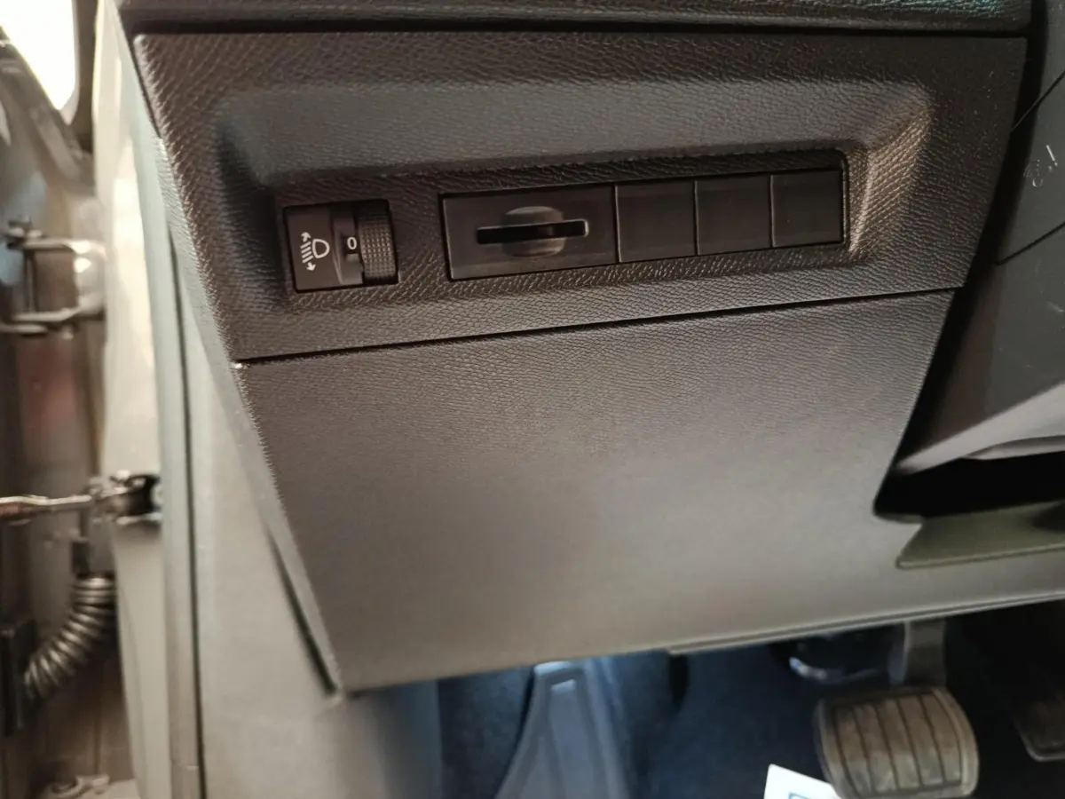 Vue intérieure côté conducteur de la Peugeot 308 blanche, montrant les commandes d'éclairage et les pédales.