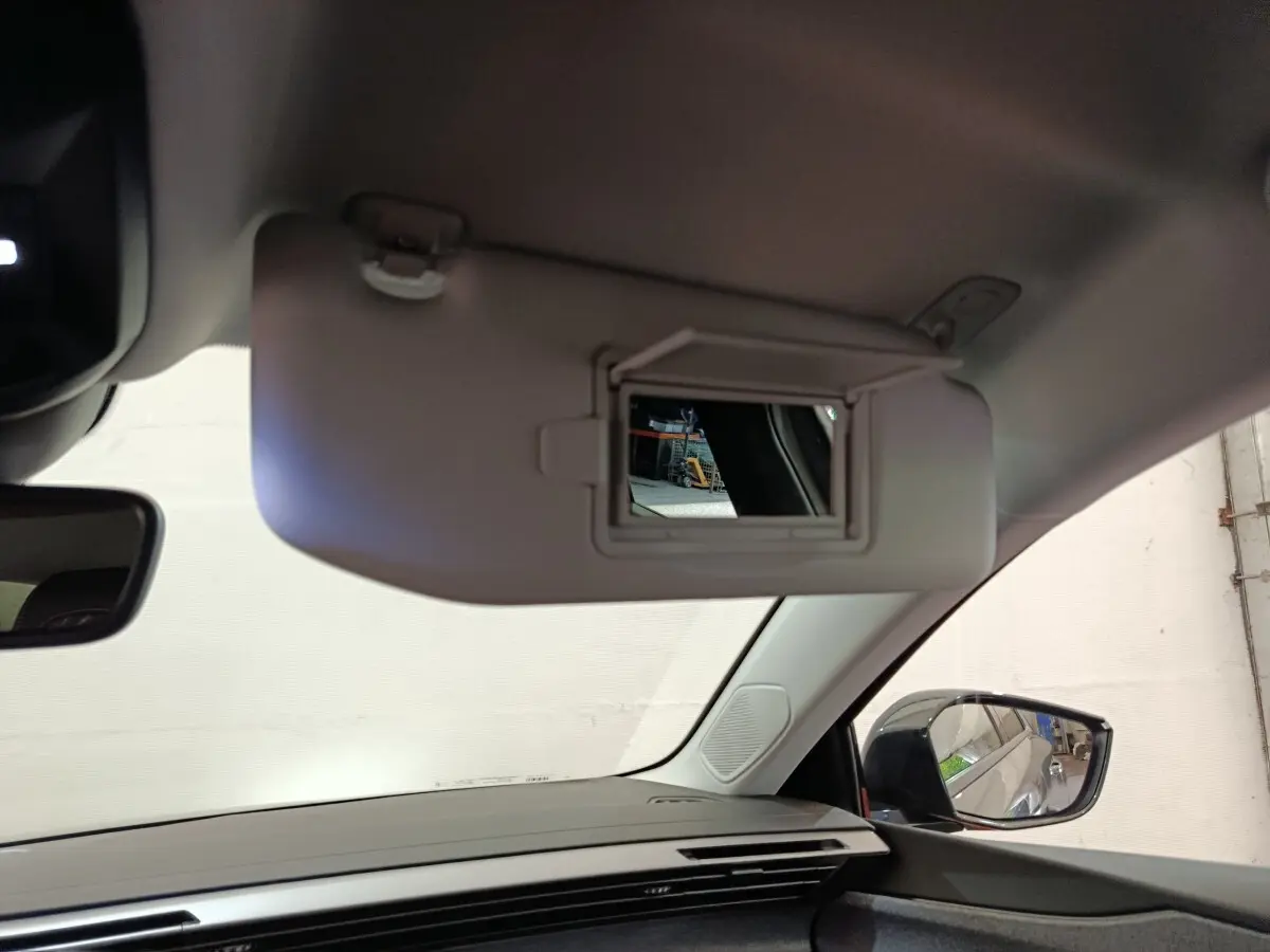 Vue intérieure côté conducteur du pare-soleil avec miroir ouvert et rétroviseur latéral droit visible d’une Peugeot 308 blanche.