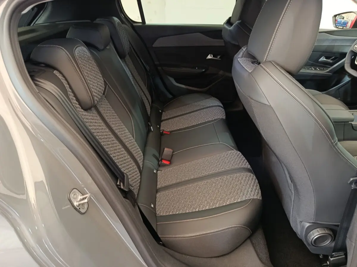Vue intérieure côté gauche montrant la banquette arrière tissu et cuir gris d'une Peugeot 308 blanche 2026.