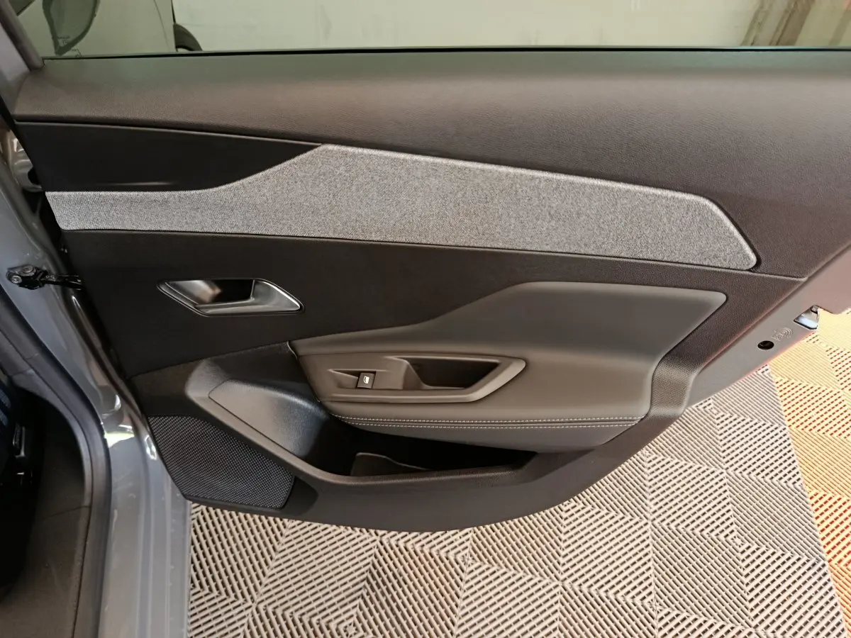 Vue intérieure de la porte avant gauche de la Peugeot 308 blanche, avec garniture tissu et cuir gris.