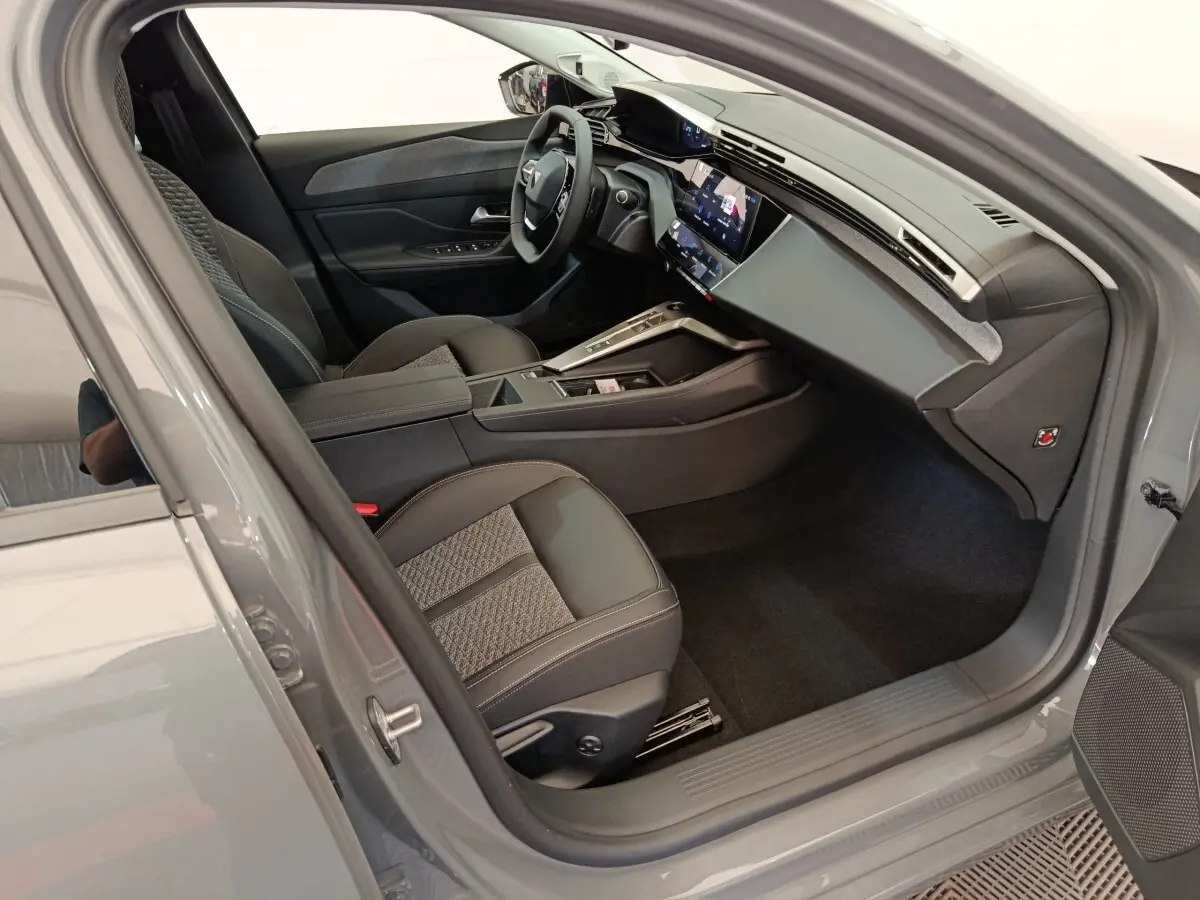 Intérieur côté conducteur de la Peugeot 308 2026, sièges cuir et tissu, tableau de bord moderne avec écran tactile.