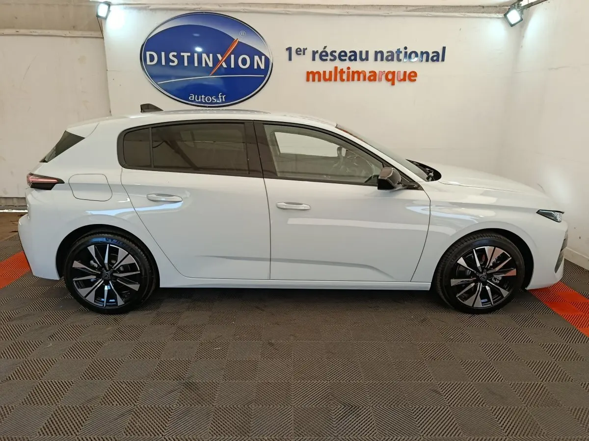 Vue de profil côté gauche d'une Peugeot 308 blanche 2026 avec jantes alliage noires et vitres teintées.