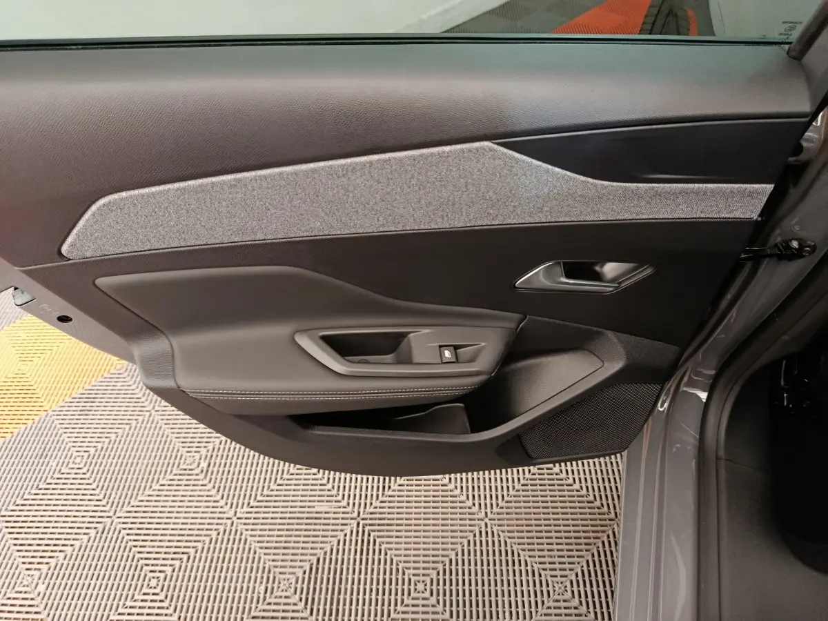 Vue intérieure de la porte avant gauche de la Peugeot 308 2026, avec garniture noire et tissu gris.