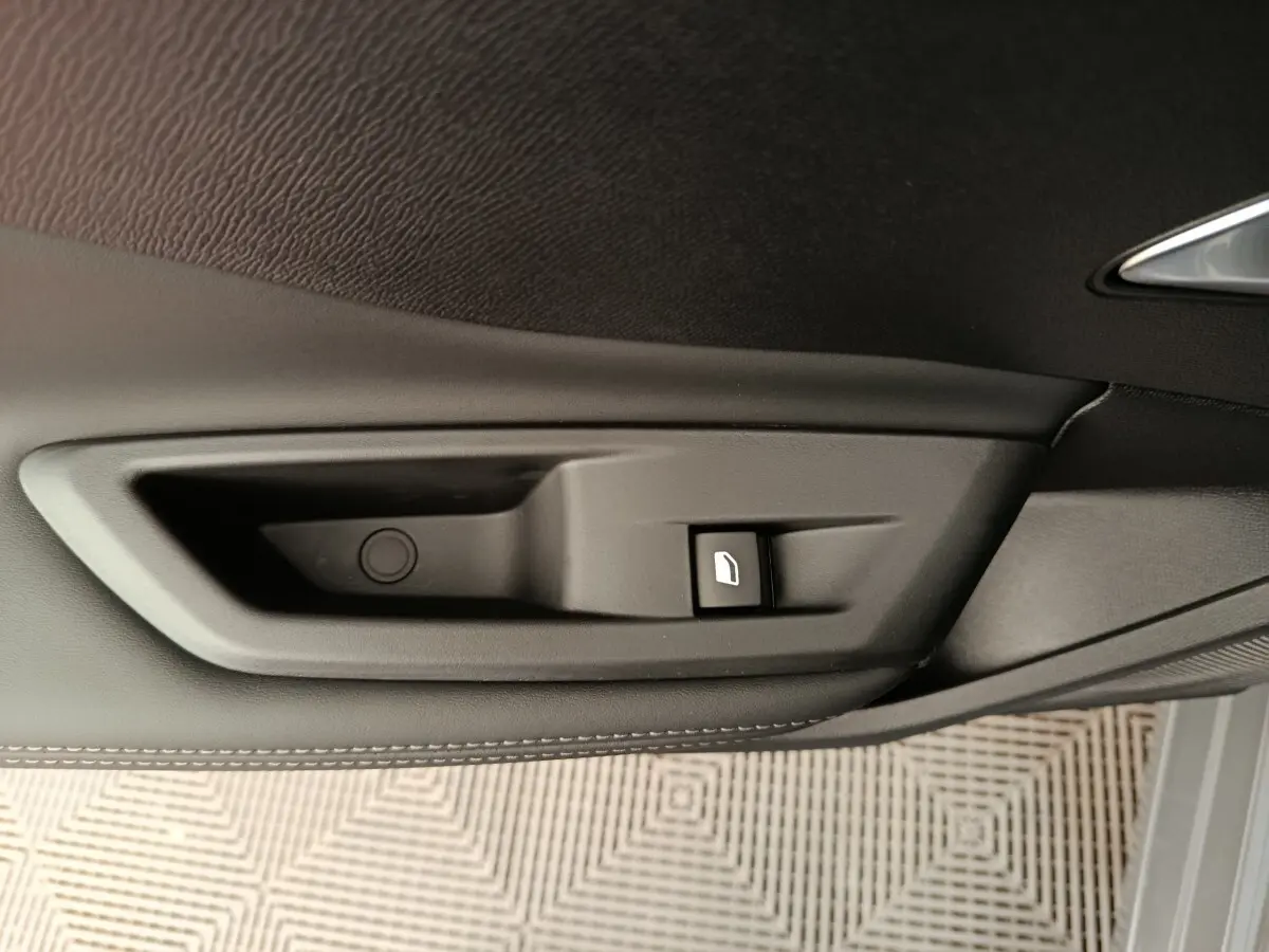 Détail de la commande de lève-vitre côté porte intérieure noire d'une Peugeot 308 blanche 2026.
