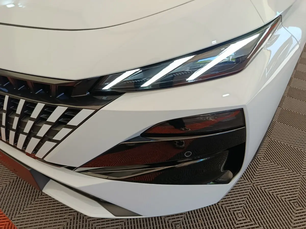 Gros plan sur l'avant droit blanc de la Peugeot 308 2026, mettant en valeur les phares LED et la calandre distinctive.