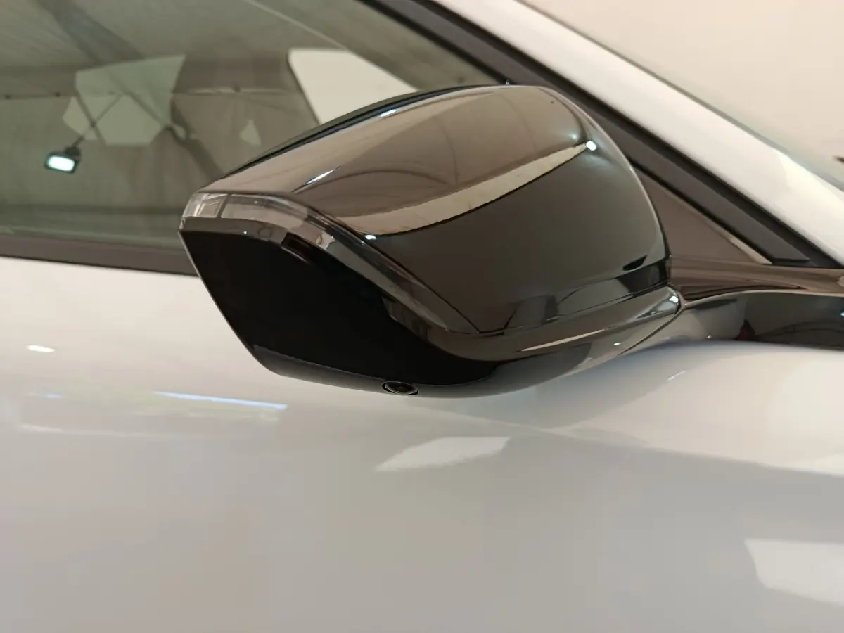 Rétroviseur noir en gros plan côté gauche sur Peugeot 308 blanche, version BlueHDi 130 CH EAT8 Allure 2026.