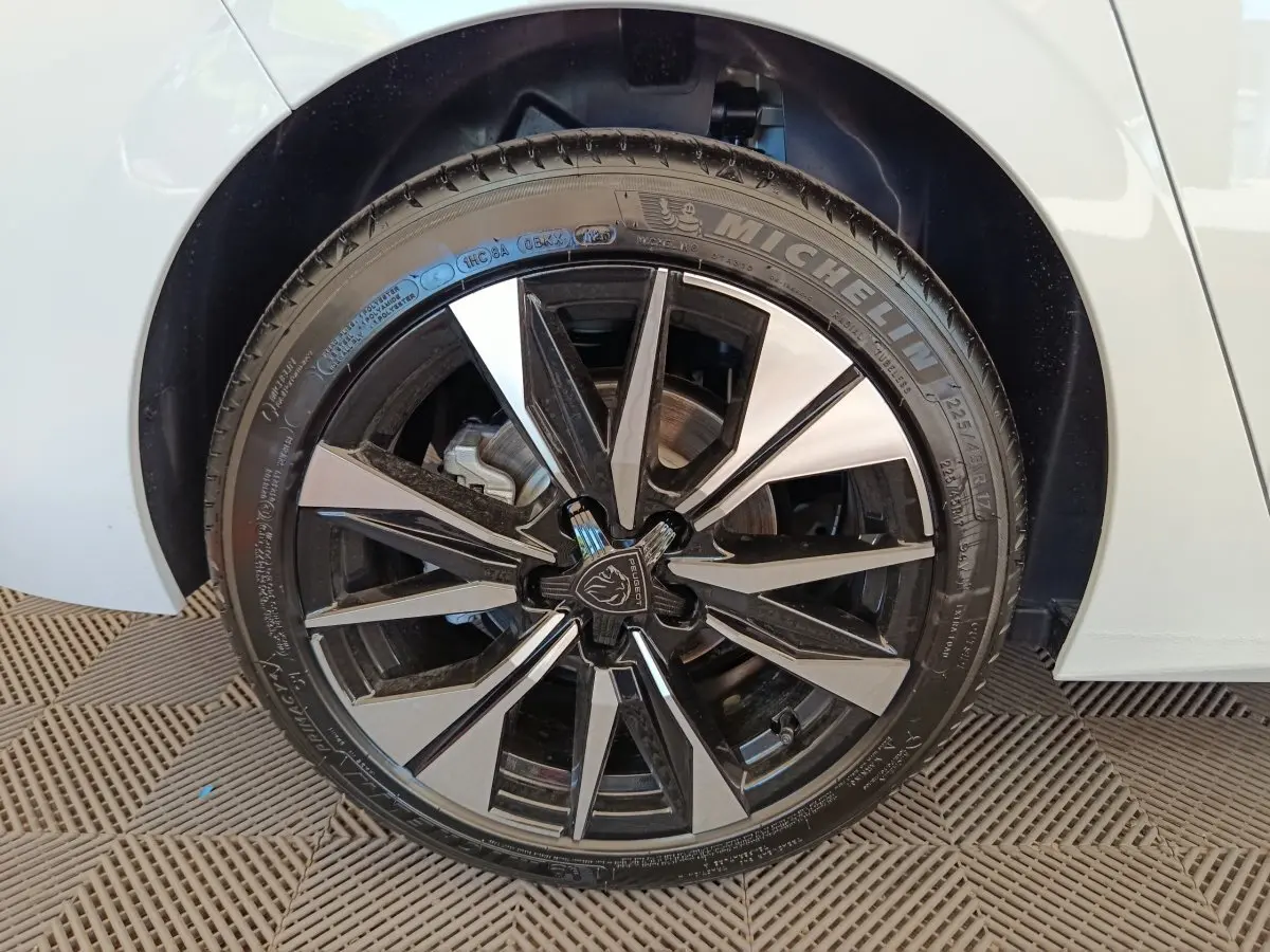 Gros plan sur la roue avant droite blanche d'une Peugeot 308 2026 avec jante alliage noire et argentée.