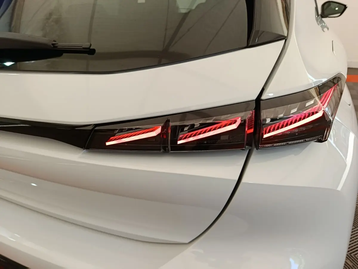 Gros plan sur le feu arrière droit rouge d’une Peugeot 308 blanche, vue arrière en intérieur.