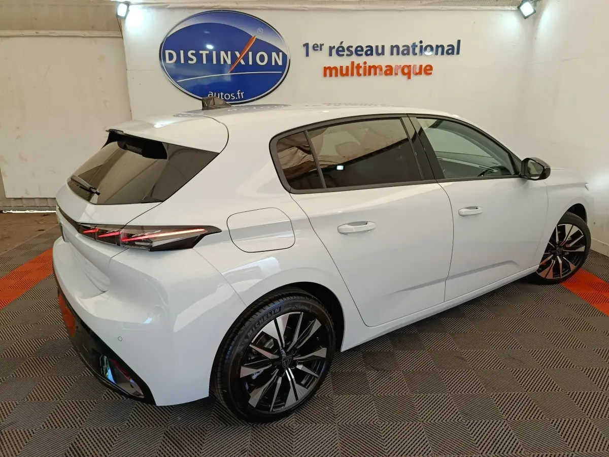 Peugeot 308 BlueHDi 130 blanc vue 3/4 arrière droit avec jantes noires et feux arrière LED distinctifs.