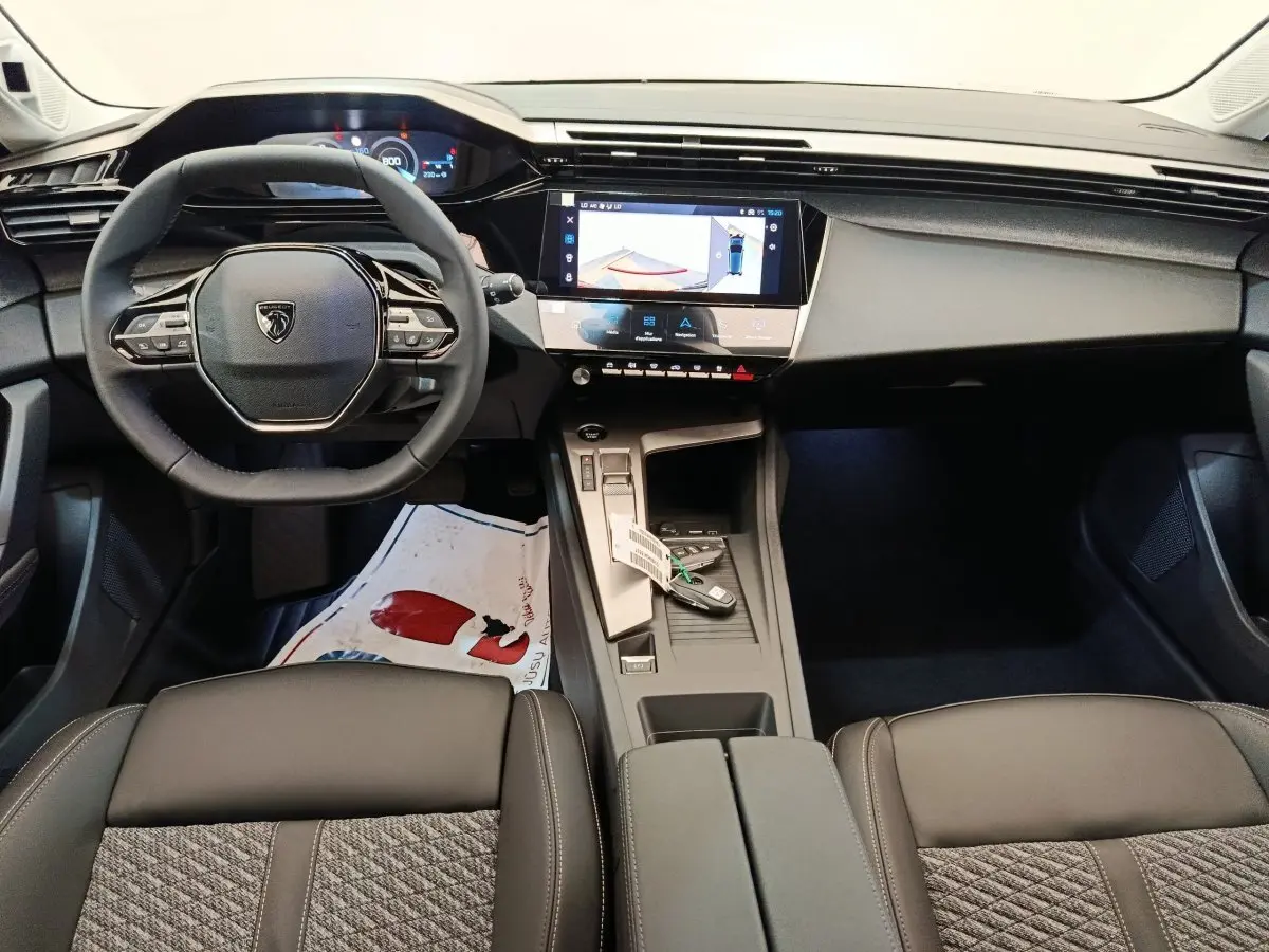 Intérieur de la Peugeot 308 2026 vue de face, volant cuir multifonctions et écran tactile central allumé.