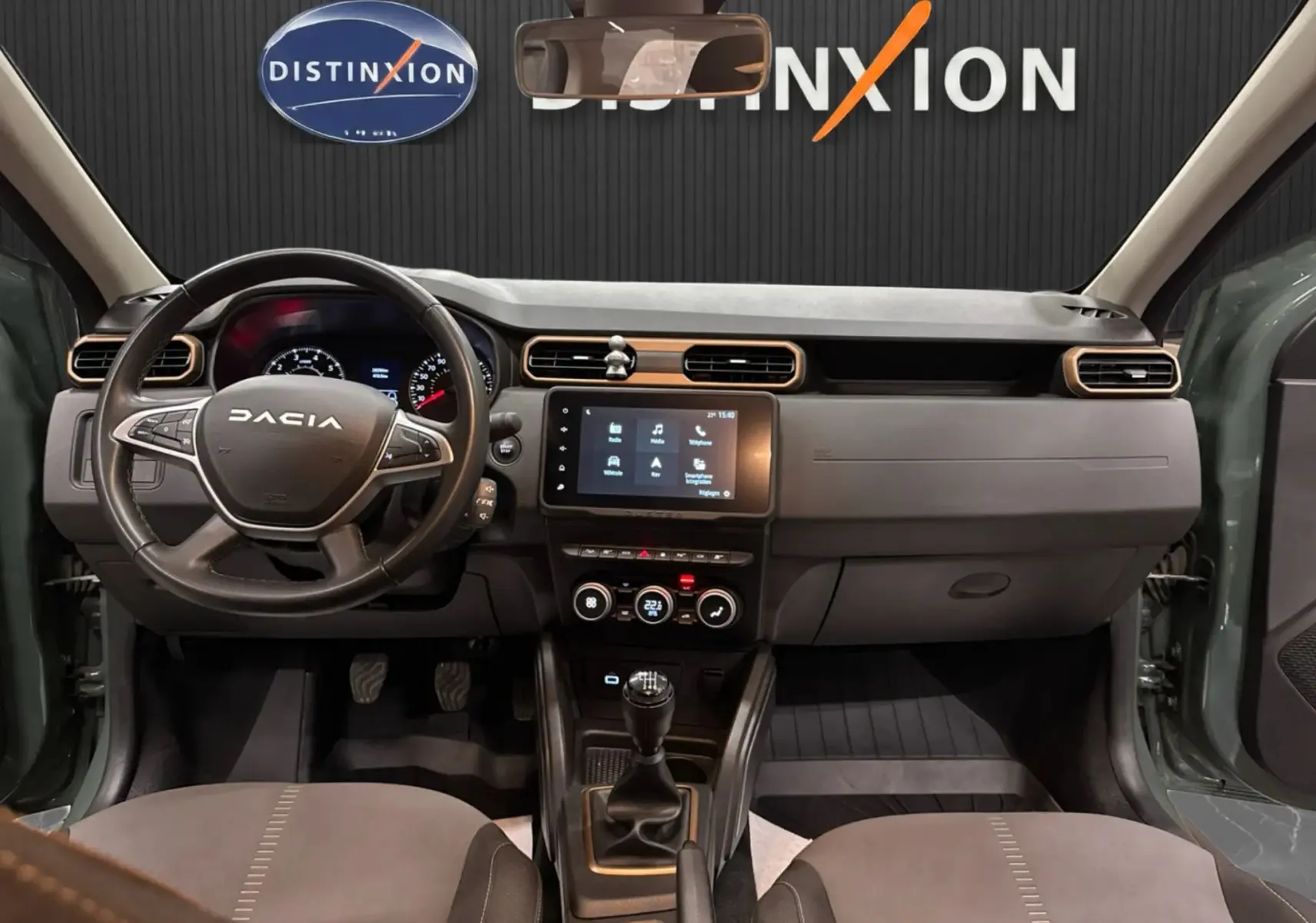 Vue intérieure avant du Dacia Duster 2024 kaki lichen, tableau de bord avec écran tactile et volant multifonction.