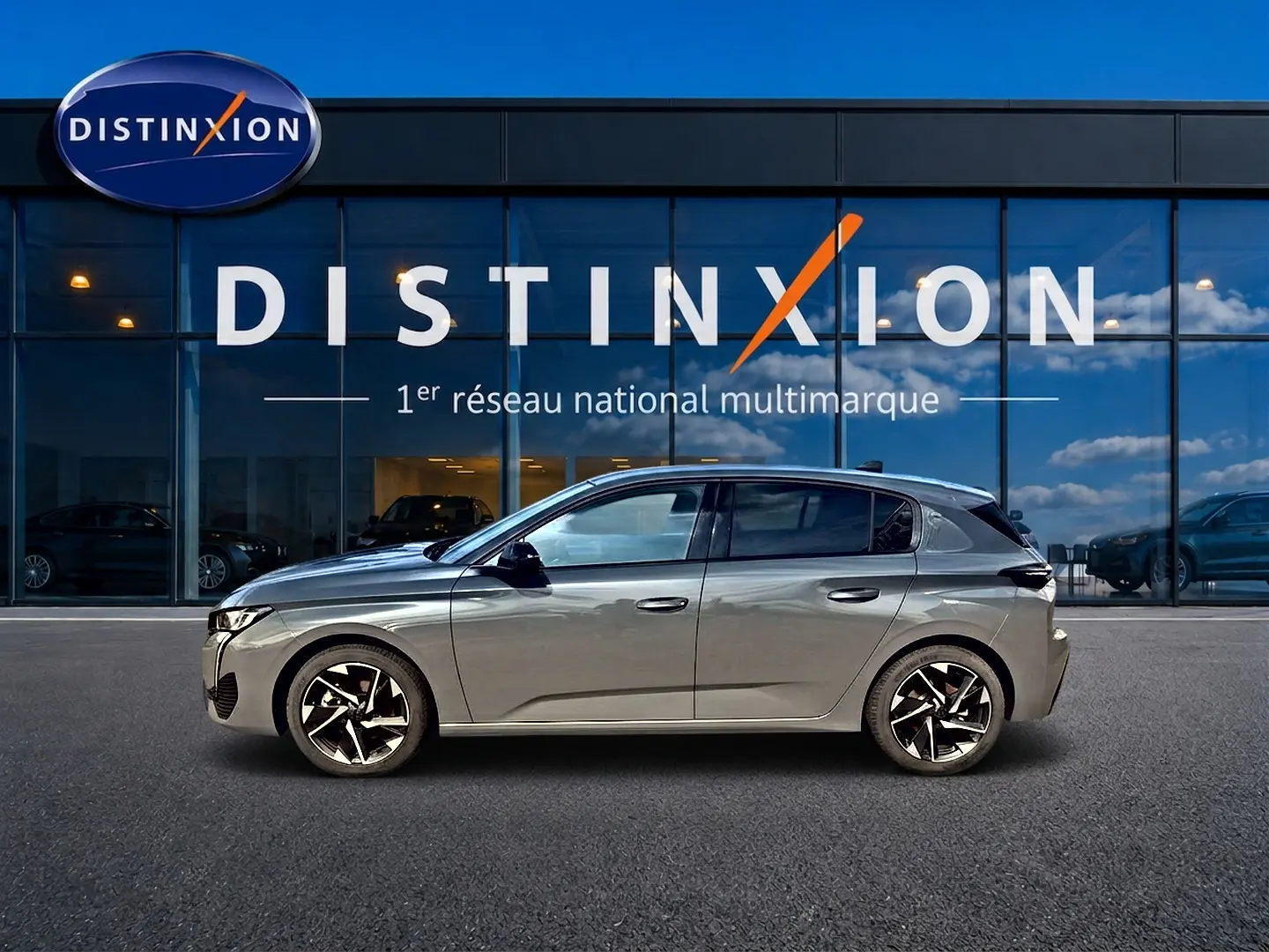 Profil droit d'une Peugeot 308 gris selenium 2025 avec jantes alliage noires et détails modernes, devant une vitrine Distinxion.